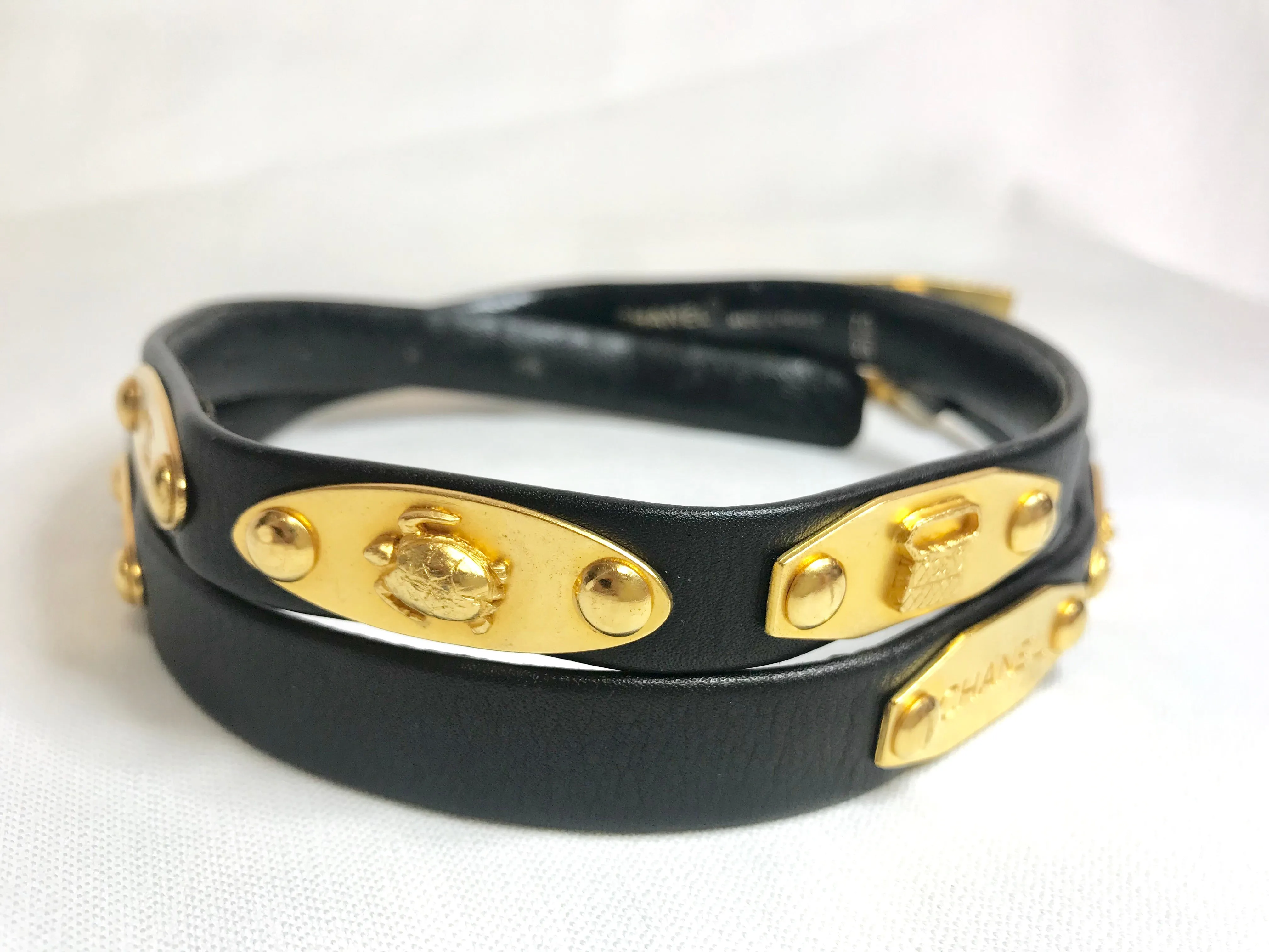 Vintage CHANEL black belt with golden buckle and iconic logo motifs, CC mark, camellia flower, turtle, perfume, clover. R0410113